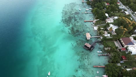 Aerial-beach-town-of-Bacalar-Mexico-resort-in-seven-colours-lagoon-with-sailboat