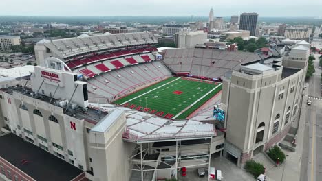 University-of-Nebraska:-Memorial-Stadium-with-its-red-seats,-green-field,-and-Lincoln-cityscape-in-the-distance