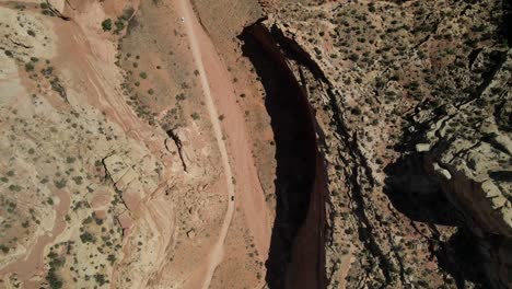 A-cinematic-overhead-view-of-Capitol-Reef,-with-a-road-cutting-through-it-and-an-indistinct-car-traveling-along-the-roadway