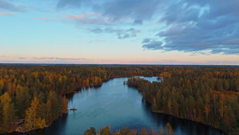 Flying-over-a-body-of-water-and-climbing-higher-to-reveal-a-lake-in-the-middle-of-an-endless-forest-in-Fiskträsk,-Sipoonkorpi-National-Park-in-Finland