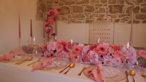indoor-barn-wedding-dinner-setting-with-pink-flower-decoration,-cinematic-dolly