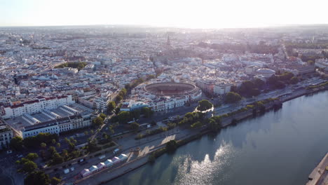 Aerial-view-over-Guadalquivir-River,-Plaza-de-Toros-and-Seville-Cathedral