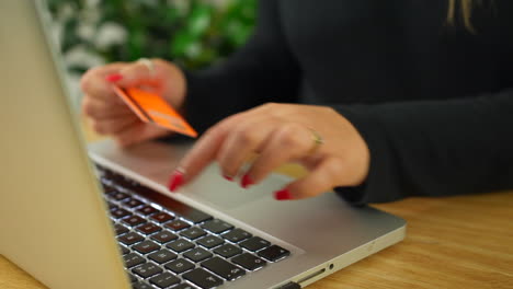 An-unrecognizable-blonde-woman-paying-online-using-a-credit-card-and-a-laptop