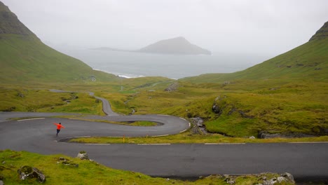 Man-running-down-Nordradalsskard-mountain-pass-with-view-of-Koltur-Island-in-Faroe-Islands