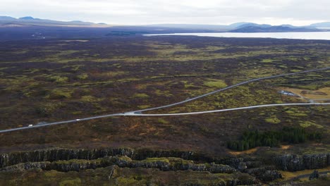 Amazing-aerial-of-Thingvellir-national-park-with-canyons-and-traffic-driving-over-long-roads