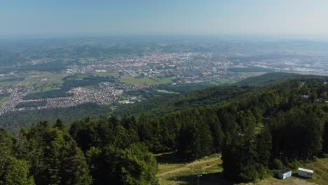 Spektakuläres-Slowenien,-Luftaufnahme-Des-Dichten-Waldes-Und-Der-Fernen-Stadt