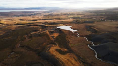 Beautiful-aerial-of-pristine-Icelandic-landscape-with-a-small-river-flowing-into-a-pond