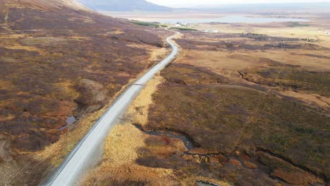 Atemberaubende-Luftaufnahme-Eines-Autos,-Das-über-Eine-Lange-Straße-Durch-Eine-Wunderschöne-Isländische-Landschaft-Fährt