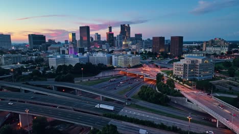 Luftaufnahme-Der-Skyline-Der-Stadt-Atlanta-Und-Des-Verkehrs-Auf-Der-Autobahnkreuzung-Bei-Goldenem-Sonnenuntergang
