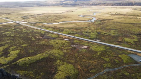 Beautiful-aerial-of-a-single-car-driving-over-highway-in-Thingvellir-Natlonal-Park,-Iceland