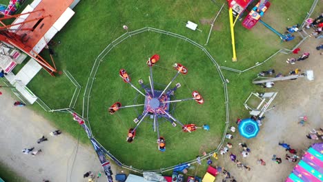 Spiral-Down-at-Amusement-Park-in-West-Virginia,-USA-with-funfair-rides-and-people