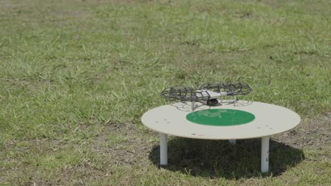 Erleben-Sie-Die-Nahtlose-Verbindung-Von-Technologie-Und-Natur-Mit-Diesem-Faszinierenden-Filmmaterial-Einer-Drohne,-Die-Eine-Präzise-Landung-Auf-Einer-Bestimmten-Landefläche-In-Einem-Weitläufigen-Feld-Durchführt
