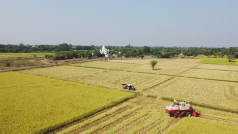 Aerial-drone-shot-of-a-harvester-machine-with-a-Sikh-Temple-in-background-in-Madhya-Pradesh-India