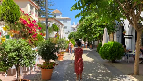 Beautiful-scenic-street-in-Estepona-old-town-with-restaurants,-colorful-flower-pots-and-green-plants,-sunny-day-in-Andalusia-Spain,-trees-and-bushes,-4K-shot
