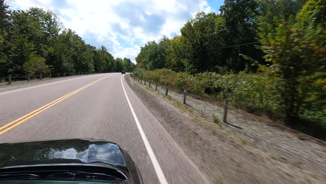Driving-view-of-Manitoulin-Island-road,-Canada,-with-lush-trees