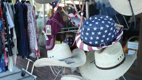 Variety-of-cowboy-hats-and-American-themed-hats-on-a-rack-outside-of-a-thrift-store