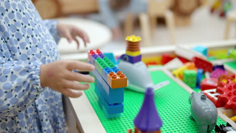 Child-Little-Girl-Playing-Constructor-Building-Wall-With-Lego-Bricks-or-Blocks---hands-close-up