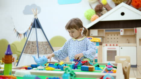 3-year-old-girl-construct-wall-from-plastic-building-blocks-or-interlocking-plastic-bricks-at-playroom