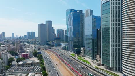 Tel-Aviv-Ayalon-freeway-traffic-and-passenger-train,-Aerial-view---Tilt-Down