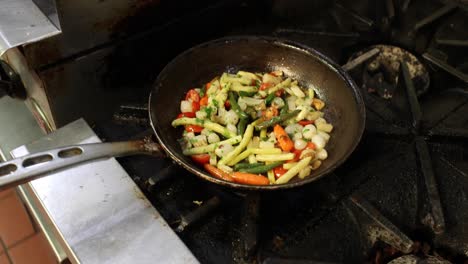 Chef-cooks-a-variety-of-vegetables-in-a-pan-on-a-stove
