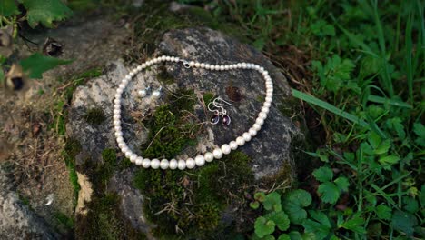 Wedding-earrings-and-pearl-necklace-for-the-bride-laid-on-a-stone-in-nature