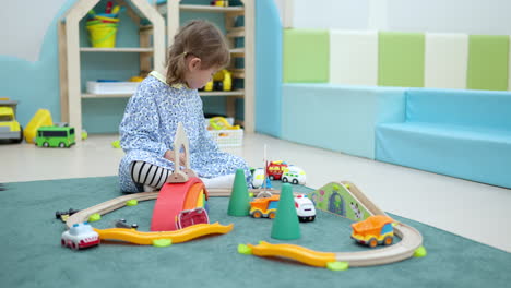 Little-girl-playing-toy-cars-racing-on-floor-at-home