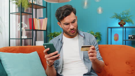 Middle-eastern-man-using-credit-bank-card,-smartphone-transferring-money-purchases-online-shopping