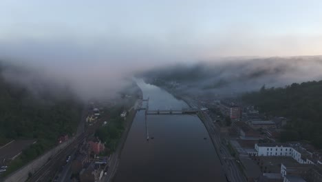 Low-clouds-at-Dinant-city-near-Maas-river-at-Sunrise,-aerial