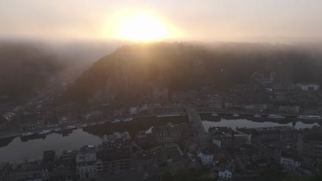 Side-panning-shot-of-City-of-Dinant-Belgium-with-fog,-aerial
