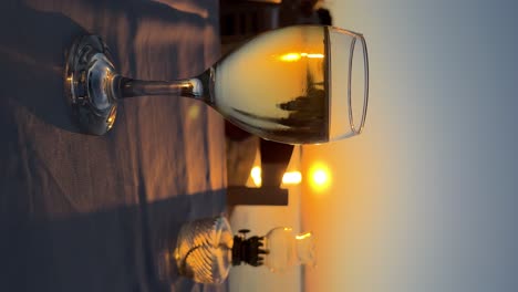 Ein-Glas-Wein-Im-Vordergrund-Und-Eine-Unscharfe-Vintage-Tischöllampe-Vor-Dem-Hintergrund-Des-Sonnenuntergangs