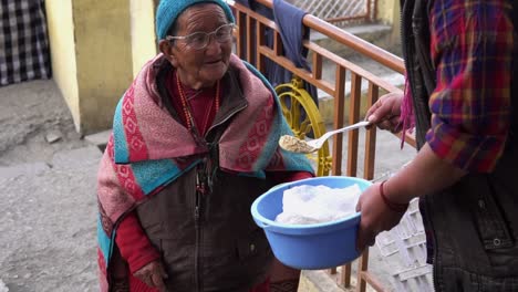 In-Spiti-or-Kaza,-a-remote-village-located-near-the-indo-china-border,-an-old-Tibetan-Lady-smiling-at-a-person-as-food-is-being-served-into-her-bowl