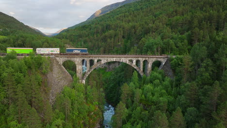 Train-crosses-iconic-Kylling-railway-bridge,-Rauma,-Norway