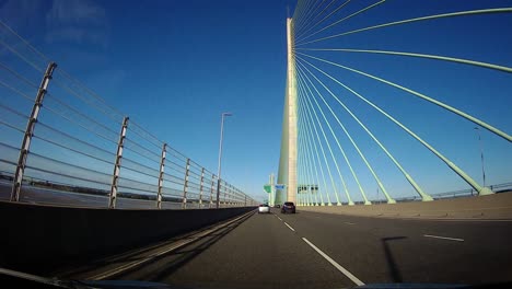 POV-dash-cam-driving-across-Mersey-gateway-bridge-in-blue-sky-sunny-morning-commute-traffic