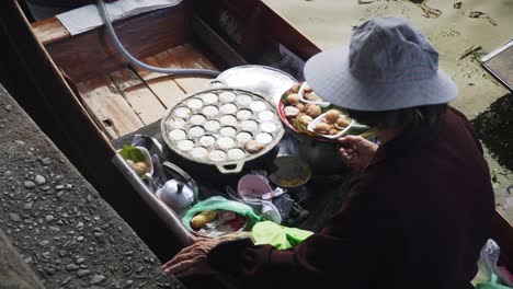 Local-vendor-selling-mini-cakes-at-Damnoen-Saduak-Floating-Market-in-Ratchaburi,-Thailand,-static-closeup