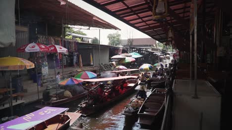 Vendors-and-passenger-boats-at-the-canal-of-Damnoen-Saduak-Floating-Market-in-Ratchaburi,-Thailand,-dynamic-jib-shot