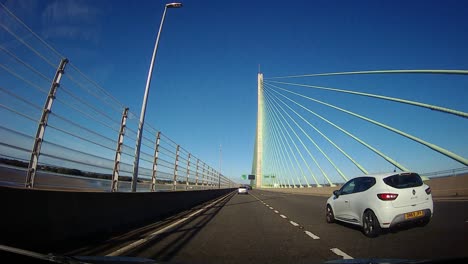 POV-dash-cam-driving-over-Mersey-gateway-bridge-in-blue-sky-sunny-morning-commute-traffic