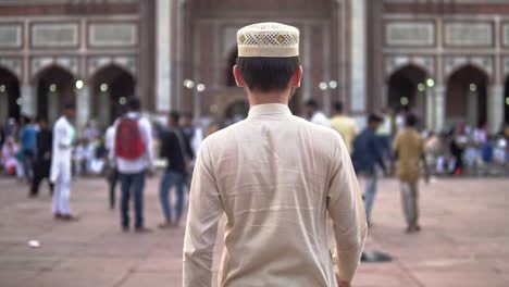 A-Muslim-boy-walking-through-the-compound-of-Juma-Masjid-in-Delhi,-India-in-a-busy-evening