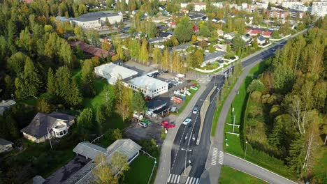 Aerial-view-of-a-pair-of-classic-and-flashy-cars-entering-a-parking-lot-in-a-rural-town-on-a-sunny-spring-day,-Kerava-in-Finland
