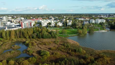 Fly-over-a-wetland-in-the-city-of-Järvenpää,-rural-skyline-on-a-sunny-and-calm-day-surrounded-by-a-pine-forest,-sustained-and-environmentally-friendly-growth
