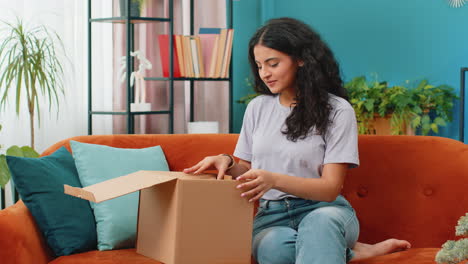 Glückliche-Arabische-Käuferin,-Die-Den-Karton-Auspackt,-Lieferung-Eines-Pakets-Online-Kauft-Und-Zu-Hause-Einkauft