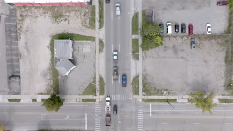 Cars-moving-at-the-intersection-of-Cedar-Street-and-Saginaw-Highway-in-Lansing,-Michigan-with-overhead-drone-video-following