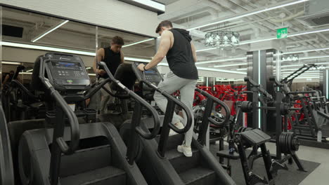 Muscular-Attractive-Man-Exercising-on-Stepmill-Machines-at-the-Gym