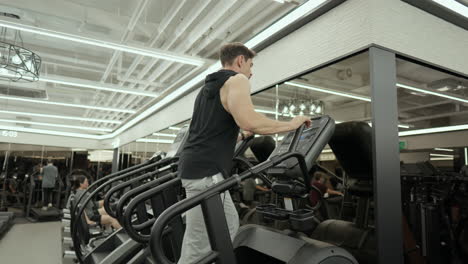 Mature-Bearded-Muscular-Man-Doing-Cardio-on-Stair-Climber-Machine-in-Fitness-Center---low-angle