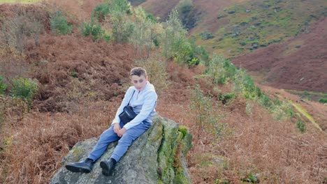 Kid-rests-on-huge-rock,-ponders-surroundings
