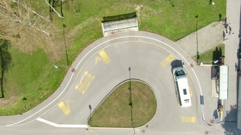 A-top-down-shot-of-a-bus-stopping-at-a-bus-station-for-a-short-moment-and-then-driving-on