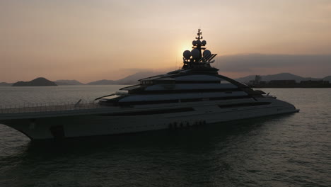 Private-Super-Yacht-Anchored-in-Hong-Kong-at-Sunset-Luxury-Boat,-CI=inematic-Circling-Drone-Shot