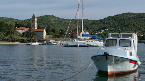 Boats-and-church-in-seaside-town-by-mountains,-Mediterranean,-Vis,-Croatia