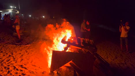 Menschen-Beim-Traditionellen-Lagerfeuer-Sommerfest-Am-Strand-Bei-Der-San-Juan-Feier-In-Marbella,-Spanien,-Genießen-Eine-Lustige-Party,-Großes-Brennendes-Feuer-Und-Heiße-Flammen-In-Der-Nacht,-4K-Aufnahme