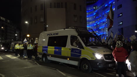 Metropolitan-police-officers-stand-in-line-and-form-a-cordon-between-two-police-vans-during-a-pro-Israel-protest-outside-the-British-Broadcasting-Corporation-offices-at-night