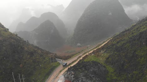 Truck-drives-on-Ma-pi-leng-pass-with-low-clouds,-aerial